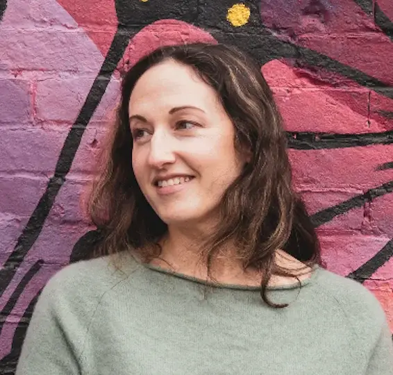 Liz Lewis, ADHD writer and coach, smiling in front of a colorful painted mural